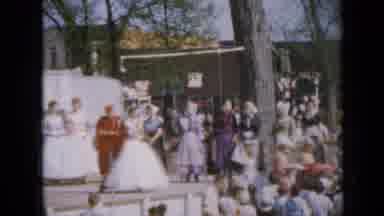 Iowa USA (1959): Lady In Dress Follows Group Of Ladies From A Stage While A Large