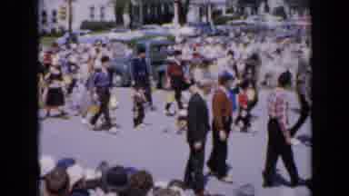 Iowa USA (1959): A Large Group Of People Sit And Stand On Both Sides Of A Street