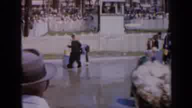 Iowa USA (1959): A Crowd Of People With Brooms Walking Around An Arena Pulling