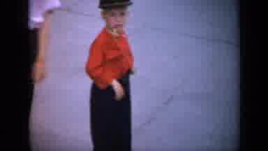 Iowa USA (1959): Small Boy In Red Shirt And Clogs Standing On A Sidewalk While