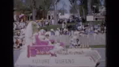 Iowa USA (1959): A Parade Of Floats Rolls Down The Street As People Line The