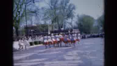 Iowa USA (1959): Group Of Women Wearing White Dresses With Red Detail Marching In