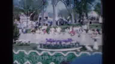 Iowa USA (1959): People On The Street Following A Celebratory Parade While A Car