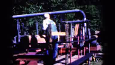 Iowa USA (1959): Man In A Hat And Overalls Working With Wooden Planks On A Machine