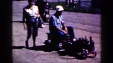 Iowa USA (1959): A Men Riding Around On The Grass While A Women Follows In The