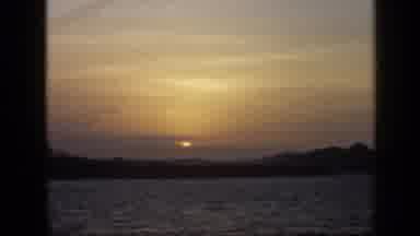 Venezuela (1959): Person Filming The Sun Setting Behind A Mountain Over The Sea