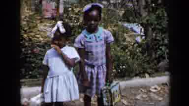 Venezuela (1959): Girl Wearing Blue Dress Holds Black And Blue Lunch Box On A