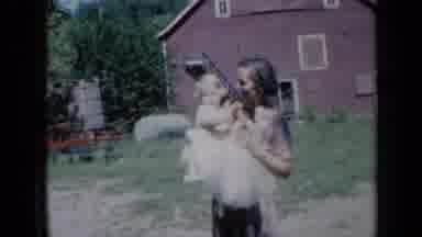 Missouri USA (1961): Woman Holds Small Girl Wearing White Dress On A Bright Sunny