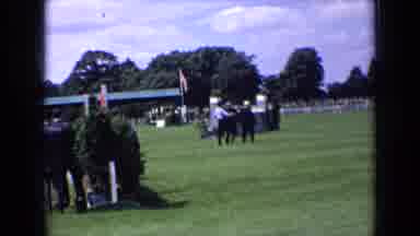 England (1963): Three Men Walk Across Green Grass On A Sunny Day