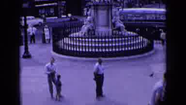 England (1963): One Man Turns And Walks In Front Of A Monument Then A Large Group