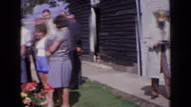 England (1963): Two Women Are Apart From A Group That Is Standing Around And Man
