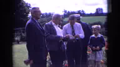 England (1963): Families Gathered Together Standing Against A White Wall And