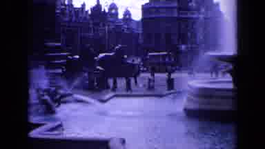 London England (1963): People And Traffic On Far Side Of Town Square With Fountain