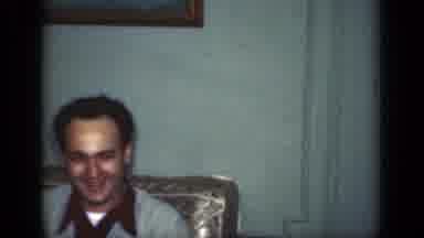 New York (1949): A Man Laughs At The Camera While Sitting On Furniture