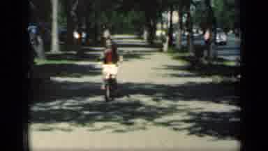 New York (1949): Girl Wearing Red Sweater Rides Bicycle On Sidewalk On A Bright