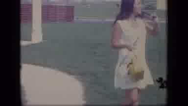 New Jersey-1970: A Woman in a White Dress Walks on a Lawn and Puts on Sunglasses