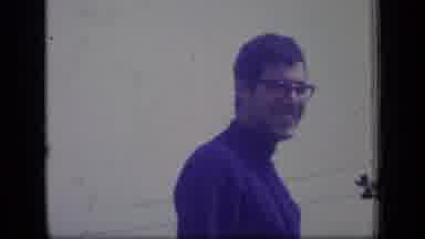 New Jersey (1970): Man Wearing Glasses And Blue Turtleneck Smiles; Women Walk By