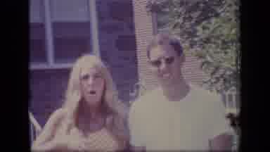 New Jersey (1970): Woman Wearing Orange Shirt Waves To Camera In Front Of Stone