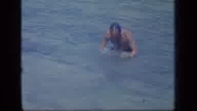 PUERTO RICO-1970: A Man In Dark Swim Shorts Getting Up Out Of The Water And Smiling