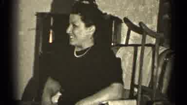 Illinois USA (1947): Woman Wearing Black Dress Watches Man Wearing Glasses Show