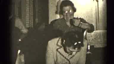 Illinois USA (1947): Woman Wearing Grey Coat And Glasses Stands Up Holding White