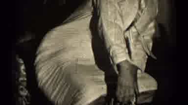 Illinois USA (1947): Young Women Wearing A White Suit Squats Down On A Chair And