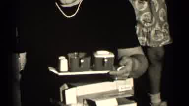 Illinois USA (1947): Woman Places Objects On A Small Tray As Girl And Man Point At
