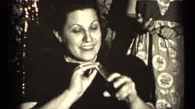 Illinois USA (1947): Woman Dabbing On Perfume In Front Of People When A Man Comes