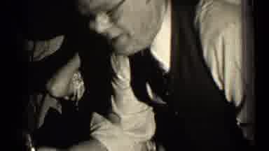 Illinois USA (1947): Woman Sitting In Chair Rubs Head Of Man Wearing Glasses