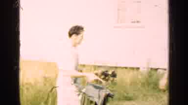 Illinois USA (1947): Man Using A Bucket To Feed A Medium Sized Black Dog