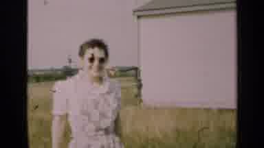 Illinois USA (1947): Woman On A Farm Pointing At A Man Using A Hand Pump Behind