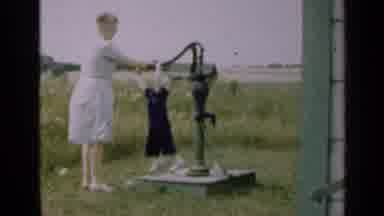 Illinois USA (1947): Woman And Child At An Open Field Pumping Water With A Men At