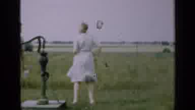 Illinois USA (1947): A Woman In A Dress Dances While A Man Pumps Water From A