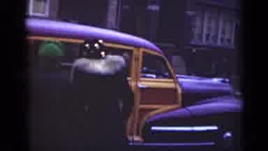 Illinois USA (1947): Woman Wearing Black Coat Walks To Brown And Yellow Car
