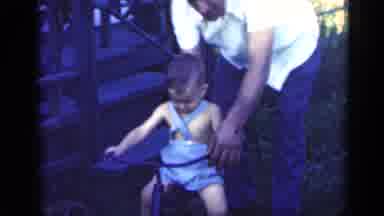 Indiana USA (1948): Little Boy Being Taught To Ride A Tricycle By His Dad Wearing