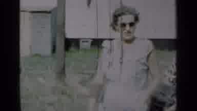 New York (1950): Woman Wearing White Dress Waves At A Green And White House On A