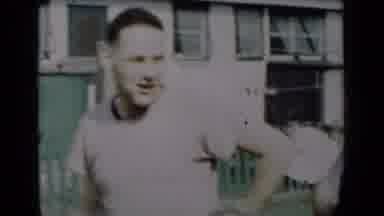 New York (1950): Man Wearing White Shirt Stands In Front Of Green Fence On A