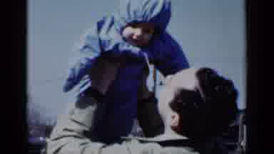 New York (1950): Father Lovingly Lifting Infant Child Dressed In Snowsuit On Cold