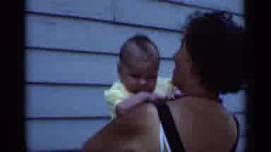 New York (1950): Woman Wearing Black Top Holds Baby Wearing Yellow Shirt On A