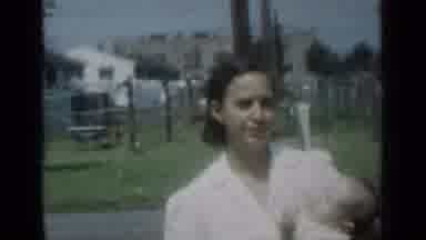 New York (1950): Woman Wearing White Dress Walks Holding Baby On A Sunny Day
