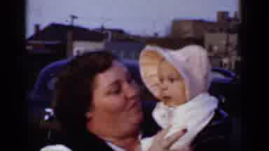 New York (1950): Woman Wearing Blue Dress Holds Baby Wearing Pink Bonnet On A