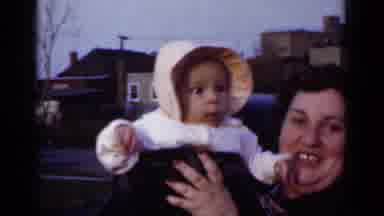 New York (1950): Lady In A Dress Holding A Baby While Smiling Into The Camera