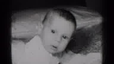 New York (1950): Baby Wearing White Shirt Looks Up At Ceiling From Floor