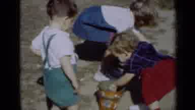 New York (1950): Boy Wearing Green Shorts Picks Up Brown Bucket On A Sunny Day