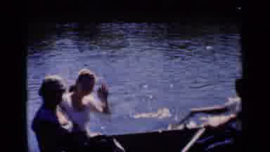 New York (1951): Two People Waving To The Camera In A Row Boat In A Body Of Water
