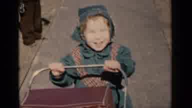 New York (1951): A Young Girl In A Green Bonnet And Matching Coat Pushes A Doll