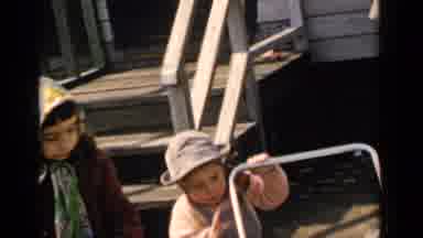 New York (1951): Little Girl In Headscarf Watches Younger Sister Play With Clothes