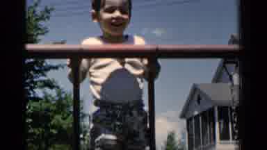 New York (1951): Boy Wearing White Shirt Leans Against Red Rail On A Bright Sunny