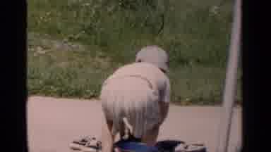 New York (1951): Boy Wearing White Shirt Tries Putting On Blue Shoe On A Bright