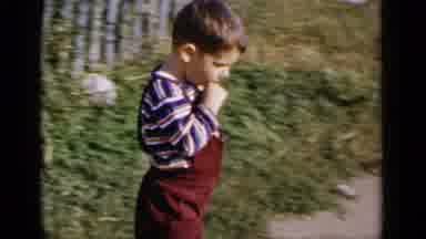 New York (1951): A Young Boy In Red Overalls And Striped T-Shirt Rides A Tricycle